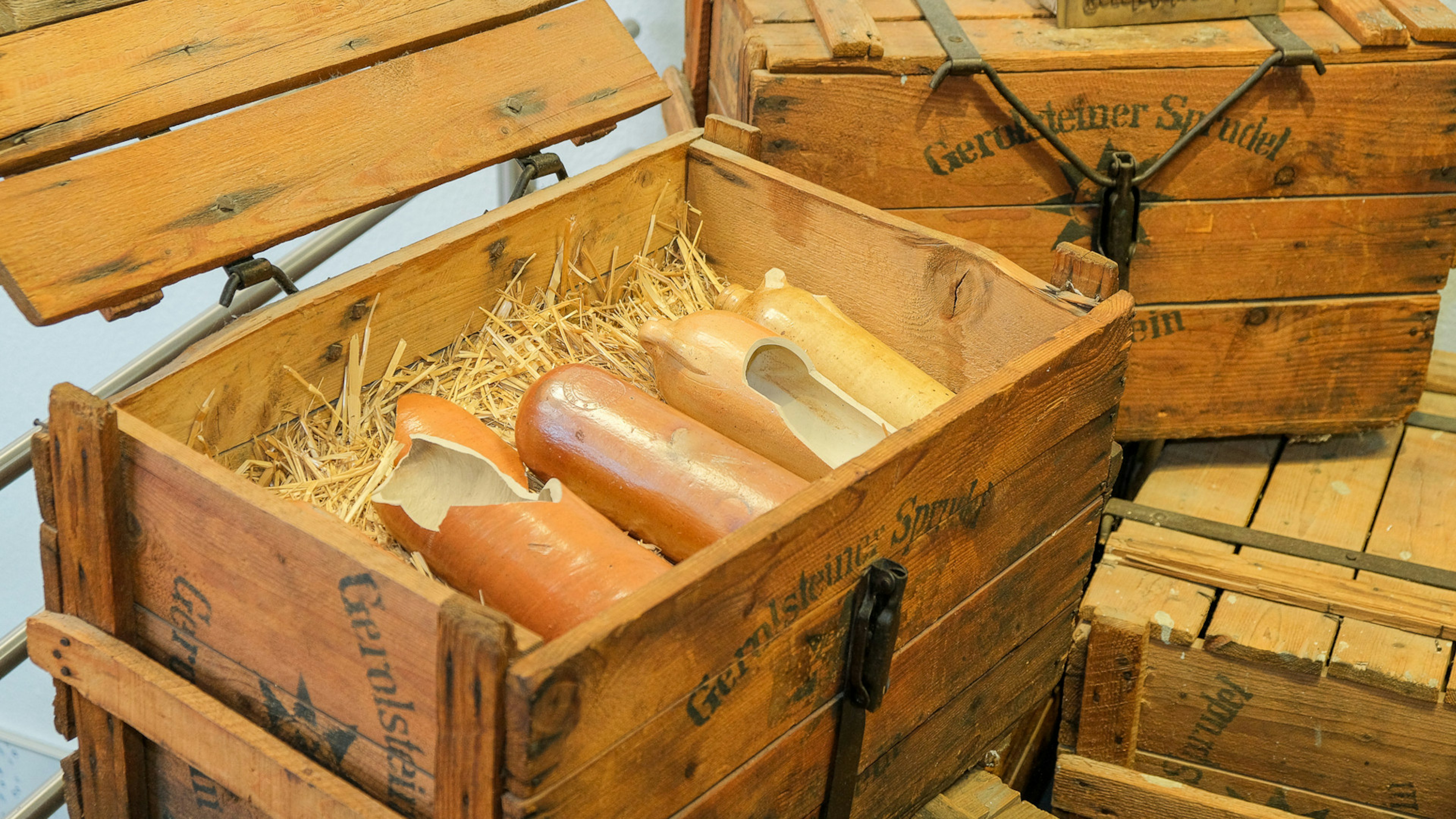 :  Eine geöffnete Holzkiste im Besucherzentrum in der die ersten Tonflaschen von Gerolsteiner liegen